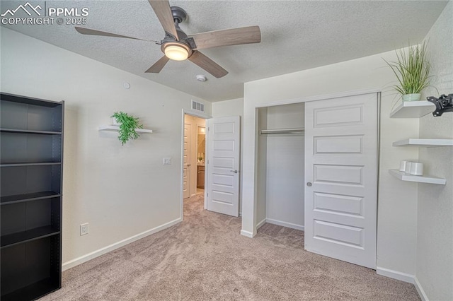 unfurnished bedroom featuring ceiling fan, a closet, light carpet, and a textured ceiling