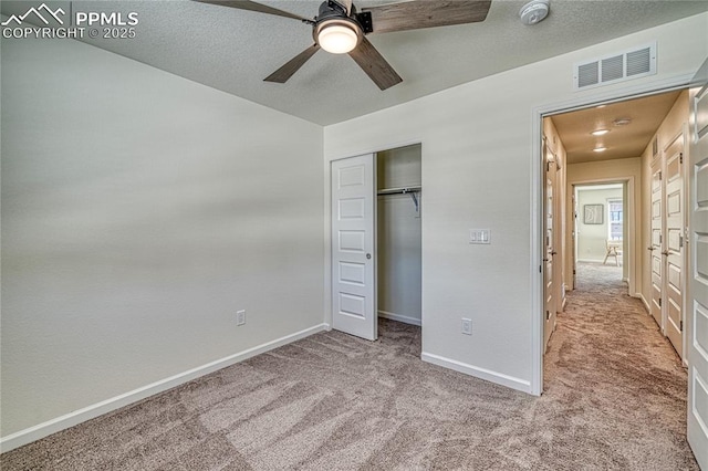 unfurnished bedroom with ceiling fan, light carpet, a textured ceiling, and a closet