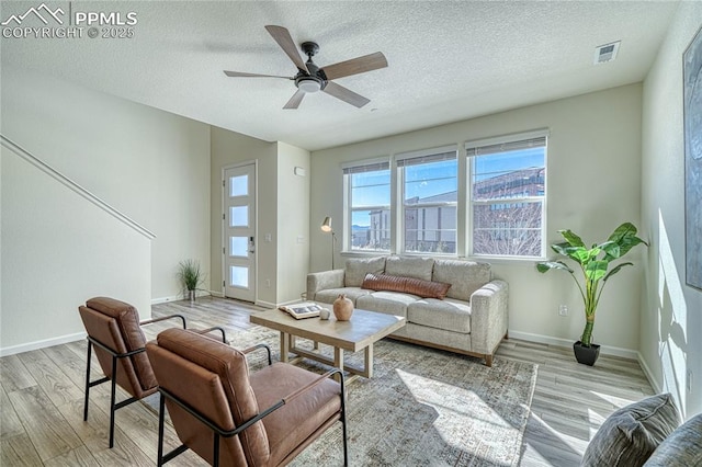 living room featuring ceiling fan, a textured ceiling, and light wood-type flooring