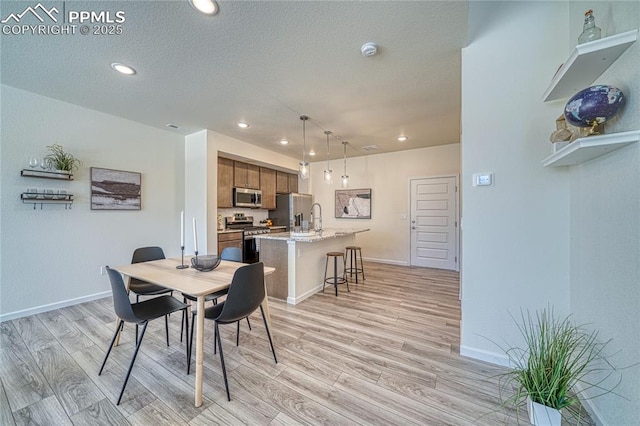 dining space featuring sink, a textured ceiling, and light hardwood / wood-style floors