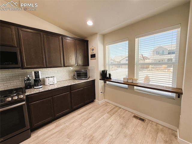 kitchen with vaulted ceiling, backsplash, light hardwood / wood-style floors, stainless steel appliances, and dark brown cabinets