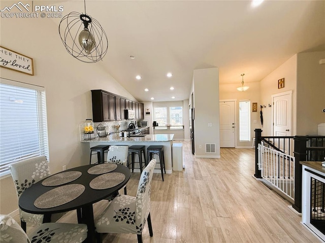 dining space featuring lofted ceiling, sink, and light hardwood / wood-style flooring