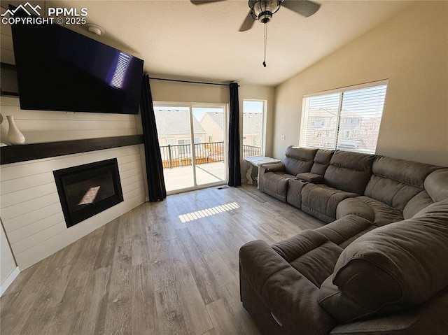 living room featuring hardwood / wood-style flooring, a large fireplace, lofted ceiling, and ceiling fan