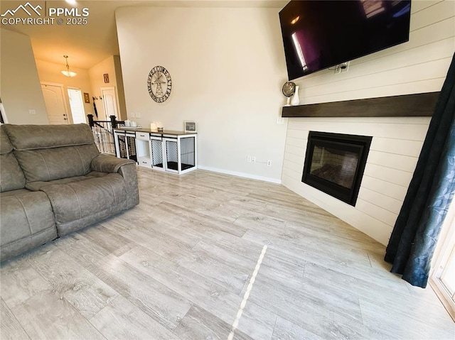 living room with lofted ceiling, a fireplace, and light wood-type flooring