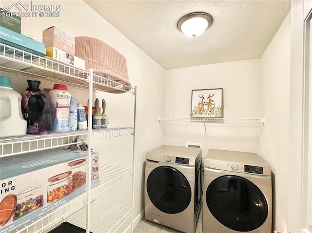 laundry area featuring separate washer and dryer, light tile patterned floors, and a textured ceiling