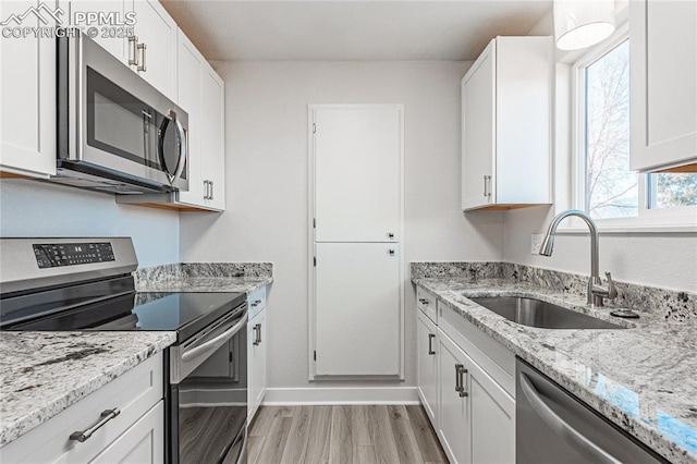 kitchen featuring sink, light hardwood / wood-style flooring, appliances with stainless steel finishes, light stone countertops, and white cabinets