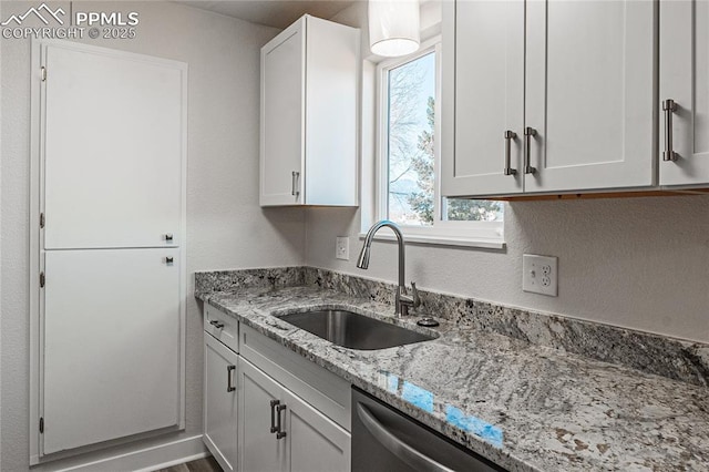 kitchen with light stone countertops, sink, dishwasher, and white cabinets