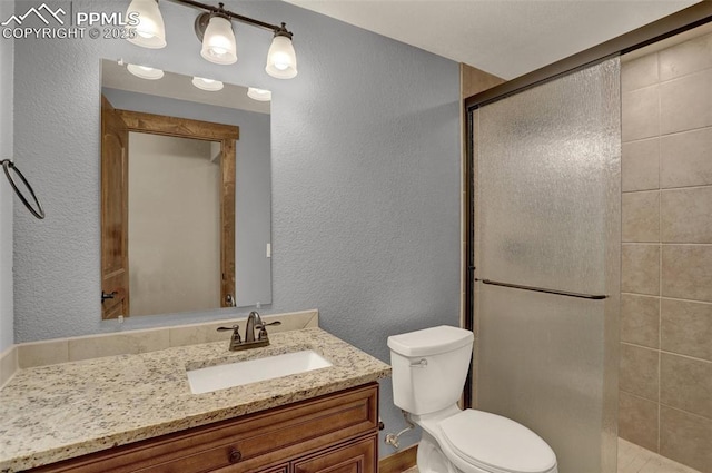 bathroom with vanity, a shower with door, and toilet