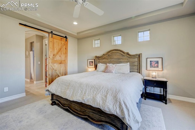 bedroom with ceiling fan, a barn door, and light carpet