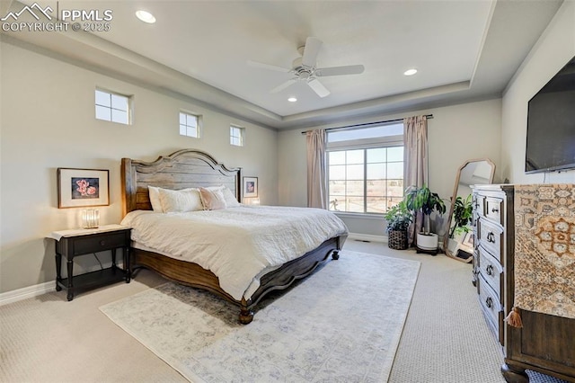 bedroom with ceiling fan, a raised ceiling, and light carpet