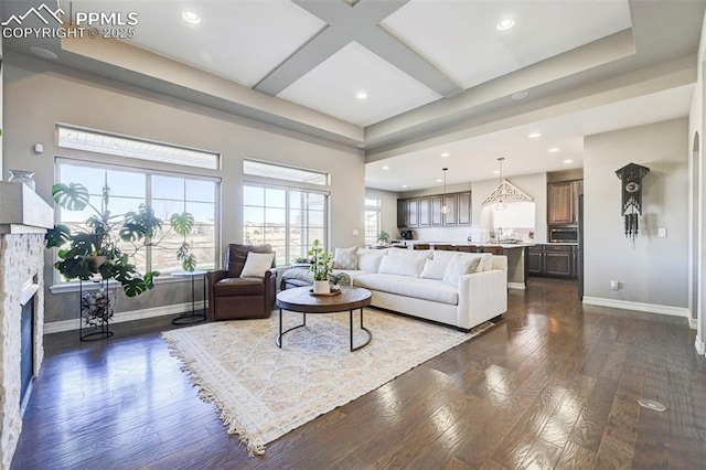 living room with beam ceiling, coffered ceiling, dark wood-type flooring, and a fireplace