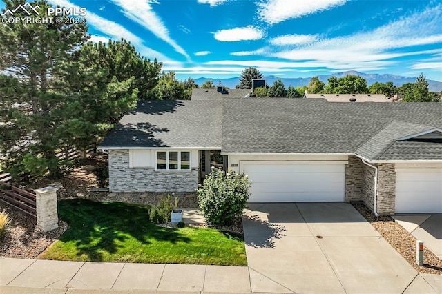 ranch-style home featuring a garage, a mountain view, and a front lawn