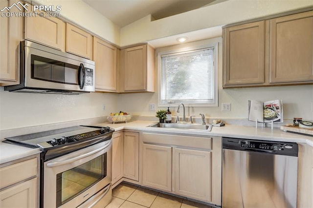 kitchen with appliances with stainless steel finishes, sink, light tile patterned floors, and light brown cabinetry