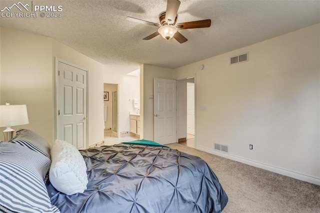 bedroom with ceiling fan, connected bathroom, light carpet, and a textured ceiling