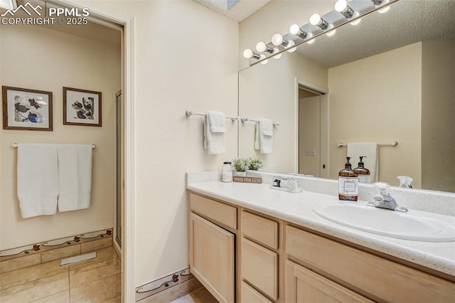 bathroom with tile patterned floors, vanity, a shower with shower door, and a textured ceiling