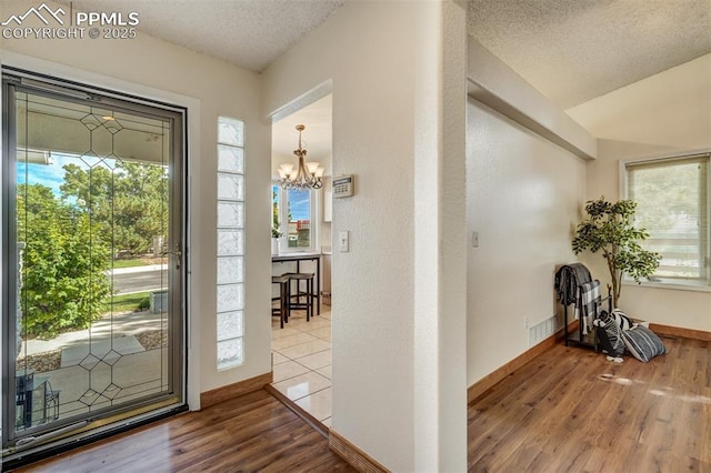 entrance foyer featuring a notable chandelier, hardwood / wood-style flooring, plenty of natural light, and a textured ceiling