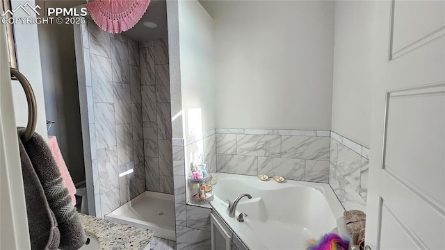 bathroom with a garden tub and a tile shower