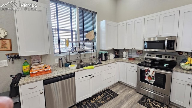 kitchen with stainless steel appliances, light wood finished floors, and white cabinetry