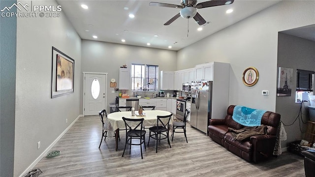 dining room featuring recessed lighting, a high ceiling, ceiling fan, light wood-type flooring, and baseboards