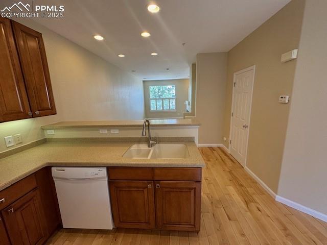 kitchen featuring sink, kitchen peninsula, white dishwasher, and light hardwood / wood-style floors