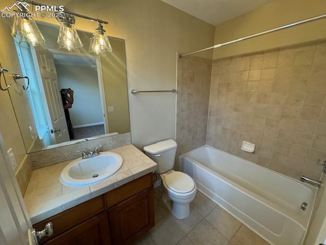 full bathroom with tiled shower / bath combo, vanity, tile patterned flooring, and toilet