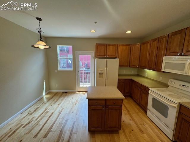 kitchen with a kitchen island, light wood-type flooring, pendant lighting, and white appliances