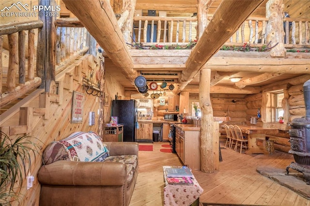 living room with beam ceiling, rustic walls, and light wood-type flooring