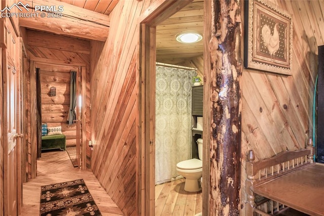 bathroom with hardwood / wood-style flooring, wooden ceiling, toilet, and rustic walls