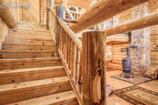 staircase featuring rustic walls and a wood stove