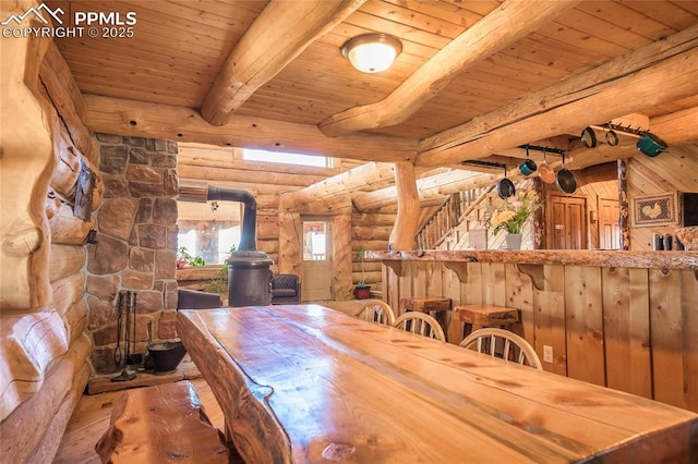 dining area with wood ceiling, hardwood / wood-style floors, log walls, beamed ceiling, and a wood stove