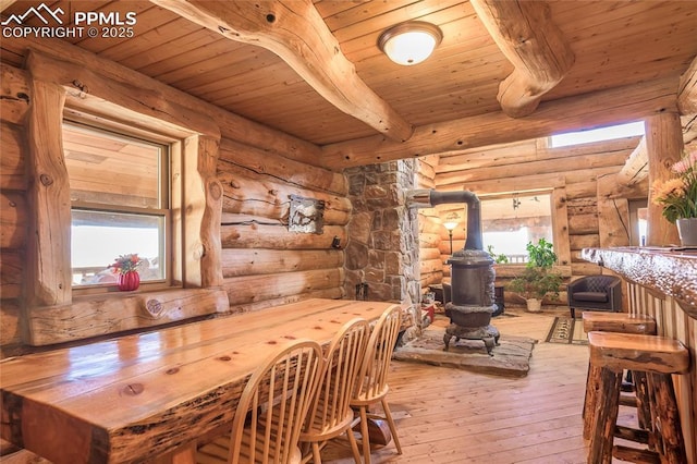 dining space featuring wood ceiling, beam ceiling, hardwood / wood-style floors, and a wood stove