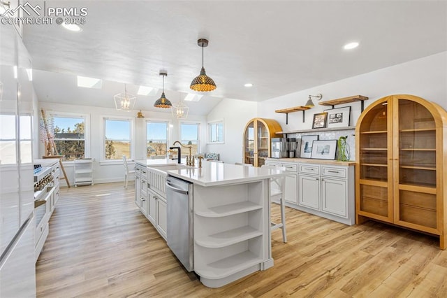 kitchen featuring pendant lighting, light hardwood / wood-style flooring, dishwasher, an island with sink, and white cabinets