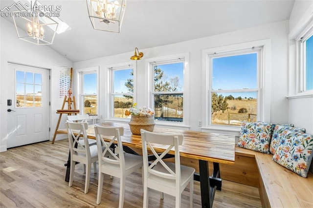 dining room featuring breakfast area, wood-type flooring, vaulted ceiling, and an inviting chandelier