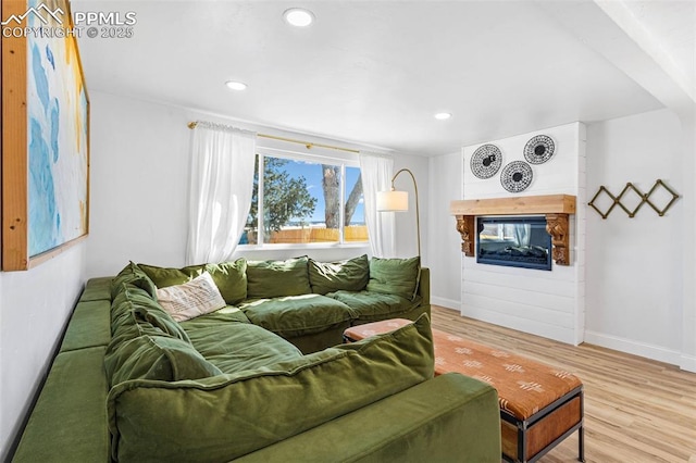 living room with a multi sided fireplace and light wood-type flooring