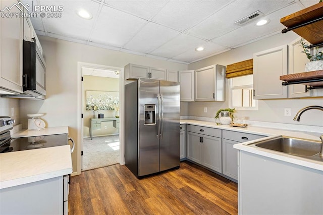 kitchen featuring sink, a paneled ceiling, appliances with stainless steel finishes, gray cabinetry, and dark hardwood / wood-style flooring