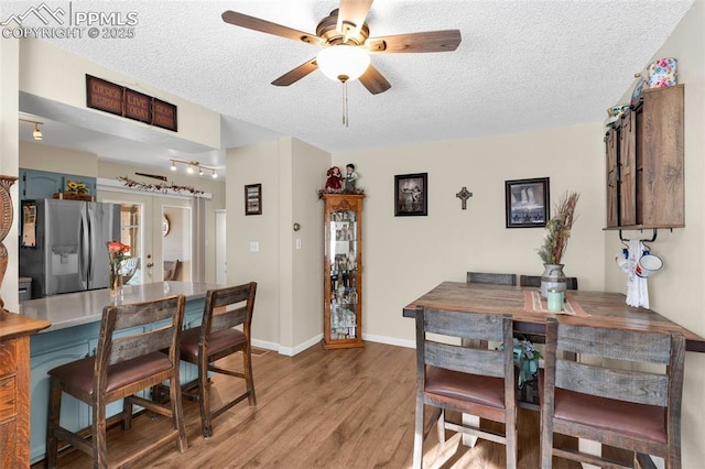 dining space with hardwood / wood-style flooring, ceiling fan, a textured ceiling, and french doors