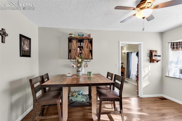 dining area with ceiling fan, hardwood / wood-style floors, and a textured ceiling