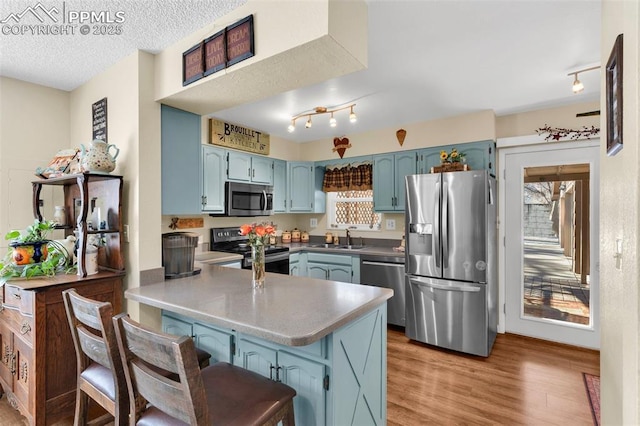 kitchen with a healthy amount of sunlight, stainless steel appliances, kitchen peninsula, and sink