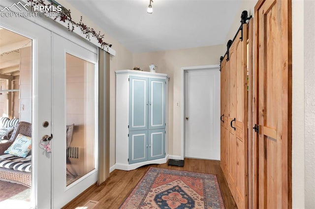 entryway featuring a barn door, light hardwood / wood-style floors, and french doors