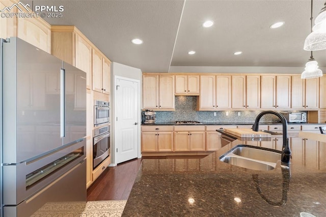 kitchen featuring sink, hanging light fixtures, stainless steel appliances, tasteful backsplash, and light brown cabinetry