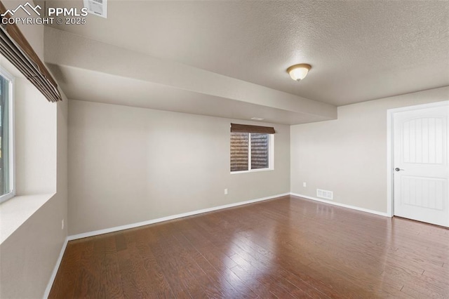 unfurnished room with dark wood-type flooring and a textured ceiling