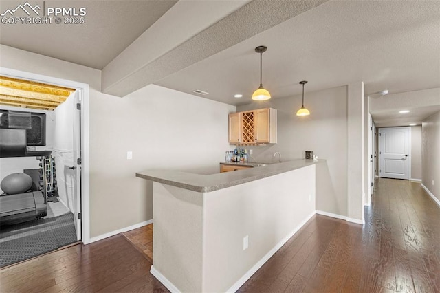 kitchen featuring sink, dark hardwood / wood-style flooring, hanging light fixtures, kitchen peninsula, and light brown cabinets