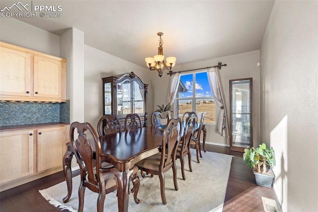 dining area with dark hardwood / wood-style floors and an inviting chandelier