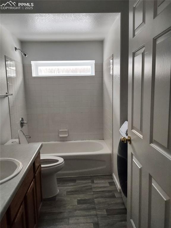 full bathroom with toilet, tiled shower / bath, wood-type flooring, a textured ceiling, and vanity