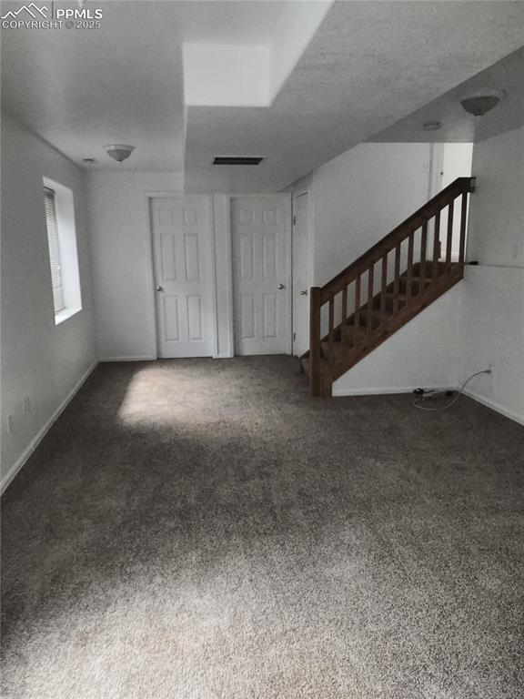 unfurnished living room featuring dark carpet