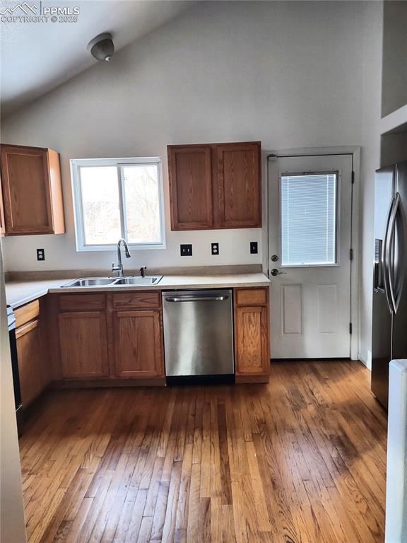 kitchen with sink, wood-type flooring, stainless steel appliances, and high vaulted ceiling