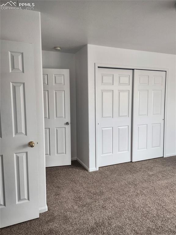 unfurnished bedroom featuring a closet and dark colored carpet