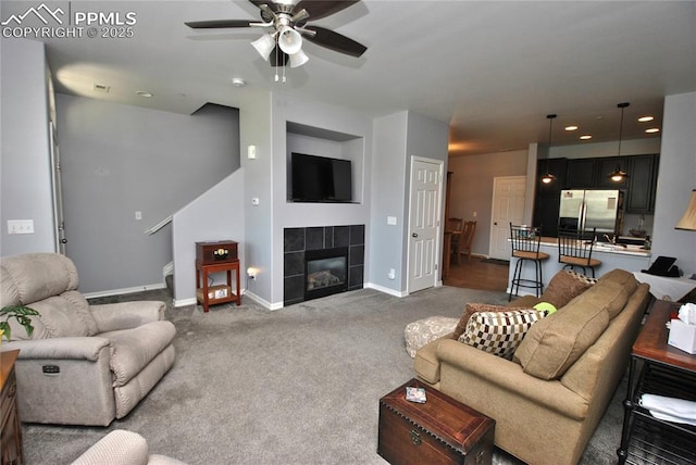 carpeted living room featuring ceiling fan and a fireplace