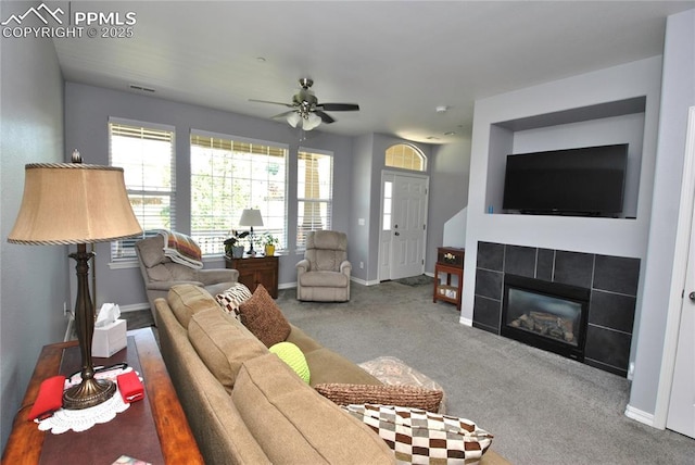 carpeted living room featuring a tile fireplace and ceiling fan