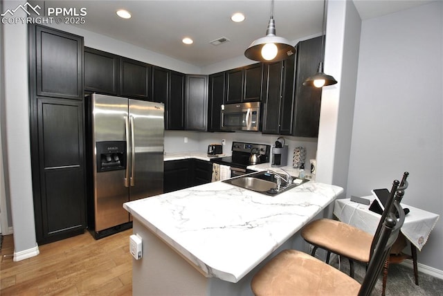 kitchen featuring appliances with stainless steel finishes, sink, a kitchen breakfast bar, hanging light fixtures, and kitchen peninsula